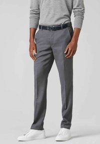 Graue, maßgeschneiderte Hosen mit glatter Textur, flacher Vorderseite und schlanker Passform, kombiniert mit weißen Sneakers und einem dunklen Gürtel.