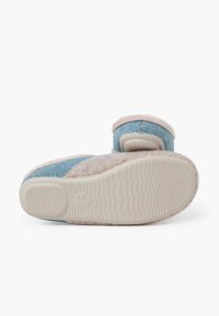 Niebieskie kapcie w wzór w jodełkę z beżowym puszystym wykończeniem i gumową podeszwą. Zaprojektowane z myślą o komforcie, z zaokrąglonym kształtem i regulowanym paskiem.