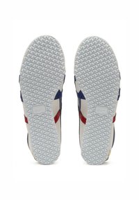 Sneaker bianche con accenti blu marino e rossi, dotate di una suola in gomma testurizzata e design antiscivolo. La suola presenta un motivo geometrico.