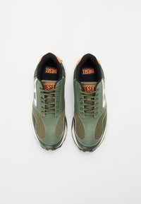 Grønn sneaker med overdelen i lær og mesh, svart fôr, oransje detaljer på hælen og hvit logo på siden. Teksturert såle for godt grep.