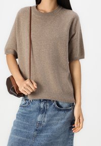 Beige, kortemouwen gebreid sweater met een ronde hals, gecombineerd met een denimrok. Inclusief een kleine bruine schoudertas.
