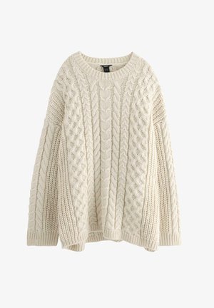 Krämfärgad stickad tröja med flätad design, rund halsringning och sänkt axel. Strukturerad tyg ger visuell närhet.