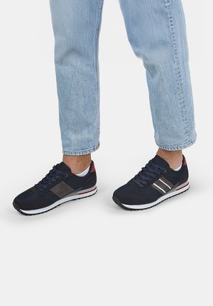 Scarpe da ginnastica navy con pannelli in rete e sintetici, dettagli argentati, intersuola bianca e suola in gomma nera. Lacci assicurati per una vestibilità ottimale.