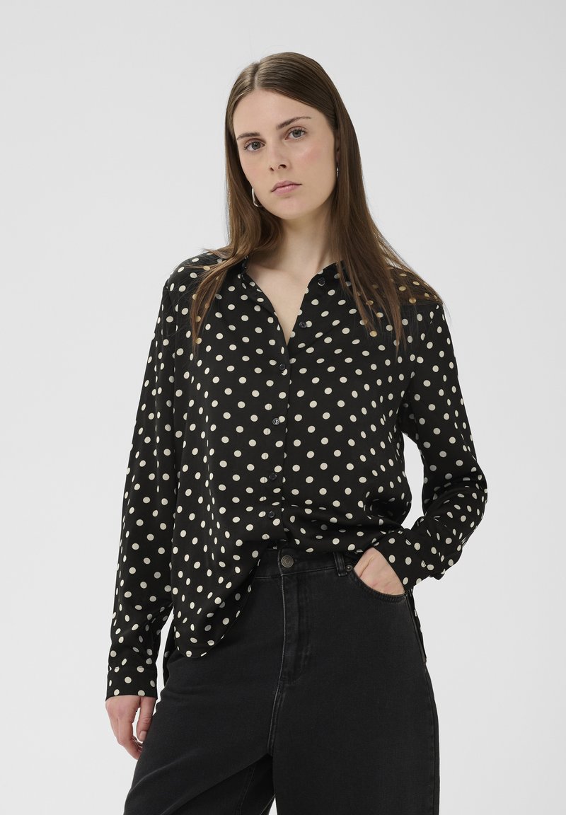 Fekete, fehér pöttyös, gombos ing, gallérral és hosszú ujjakkal. Magas derekú sötét farmerral viselve, lazább szabással.