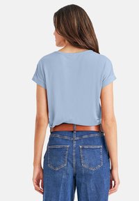 Lichtblauw kortemouwen top met een relaxte pasvorm, gecombineerd met hoog-waisted blauwe denim jeans en een bruine riem, met achterdetails.