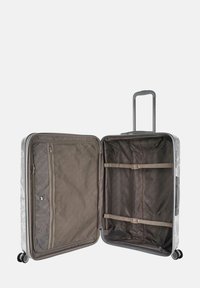 Equipaje de carcasa dura en gris mate con un interior estampado. Cuenta con un asa retráctil, bolsillos con cremallera y correas de compresión.