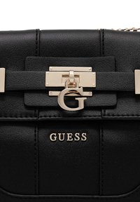 Borsa nera in similpelle con chiusura in metallo color oro, logo "GUESS" impresso e una texture liscia con design strutturato.