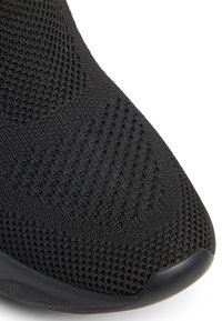Black athletic shoe with a textured mesh upper, featuring a rounded toe and smooth rubber sole, designed for comfort and flexibility.