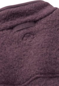 Weiches lila Fleecegewebe mit einem gestickten runden Logo und einer Stoffschlaufe in der Nähe des Kragens zum Aufhängen.