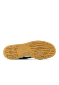 Gröna sneakers med en sula av gummigummi som har ett texturerat mönster. Yttersulan har en logotyp och olika mönster för grepp.