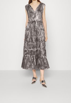 Srebrna plisowana sukienka midi bez rękawów z warstwowymi falbanami i dekoltem w kształcie litery V, zestawiona z błyszczącymi srebrnymi butami na obcasie z pointed toe.