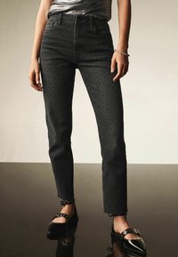 Musthave musteleassid, kõrge talje, strege katus, frayed hem. Must musteleassid, milles on hästi sobitavad jalatsid ning ülevalt kinni hoidev lukk.