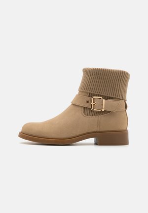 Beige bokacsizmák bordázott kötött mandzsettával, velúros hatással, oldalsó csattal és alacsony négyzetes sarokkal.