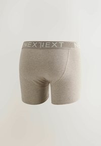 Boxer briefs para hombre en color beige con una cinturilla elástica ancha que muestra el nombre de la marca "NEXT" en texto claro.