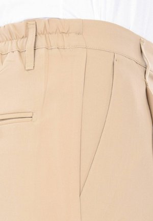 Pantaloni beige realizzati in tessuto morbido, dotati di una cintura flessibile, tasche laterali e una texture liscia con una vestibilità sagomata.
