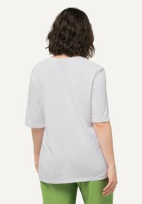 Camiseta blanca de manga corta con un corte holgado y puños enrollados, que presenta una tela texturizada y un cuello redondo.