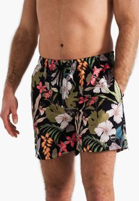 Zwarte zwembroek met een levendig bloemenpatroon in wit, roze en groene tinten. Elastische tailleband met koord; logodetail op de zoom.
