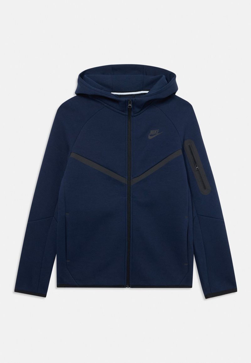Sweatshirt com capuz azul marinho e fecho éclair, apresentando uma faixa diagonal preta no peito e um bolso lateral com fecho éclair. Logótipo da Nike no peito.