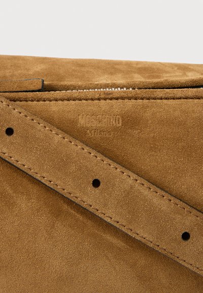 Καφέ τσάντα από σουέντ με ραμμένο λουρί και ανάγλυφο λογότυπο "Moschino Milano" κοντά στο φερμουάρ.