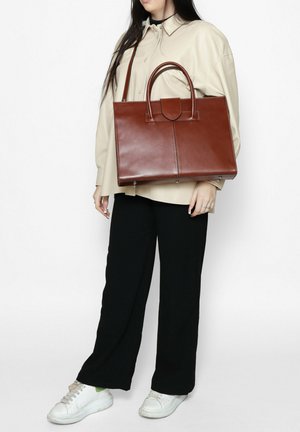 Bruine leren tote bag met een gestructureerd ontwerp, dubbele handgrepen bovenaan en een centraal paneel, met een gladde textuur en minimale hardware.