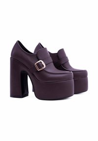 Tacchi a piattaforma viola scuro con un ampio tacco a blocco, materiale sintetico liscia e una cinghia con dettagli di fibbia dorata.