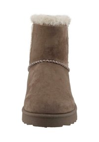 Bruine suedelaarzen tot de enkel met een gestructureerde, zachte bontvoering aan de bovenkant, gestikte details rond de bovenkant en een rubberen zool.