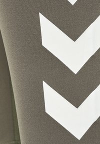 Olivgröna leggings med ribbad textur som har stora vita chevronmönster på sidan. Tyget verkar elastiskt och hållbart.