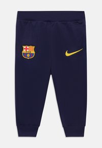 Mörkblå FC Barcelona barnbyxor med elastisk midja, FC Barcelona-vapnet på vänster ben och gul Nike-logotyp på höger ben.