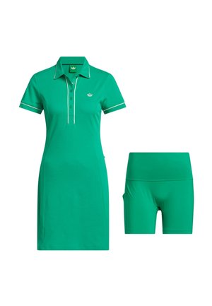 Vestito polo verde a maniche corte con rifiniture bianche e logo, abbinato a pantaloncini aderenti verdi a vita alta coordinati.