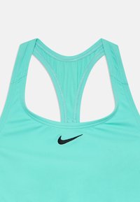Tirkīza sporta krūšturis ar racerback dizainu, ar melnu Nike logotipu. Gluda auduma ar redzamām šuvju detaļām.