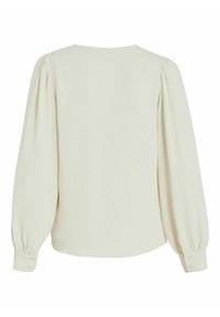 Blouse à manches longues de couleur crème avec épaules bouffantes et poignets boutonnés, vue de dos sur fond blanc.