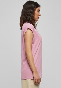 Roze T-shirt met korte mouwen, een losse pasvorm en opgerolde manchetten. Gemaakt van zachte stof, gladde textuur en eenvoudige silhouet.