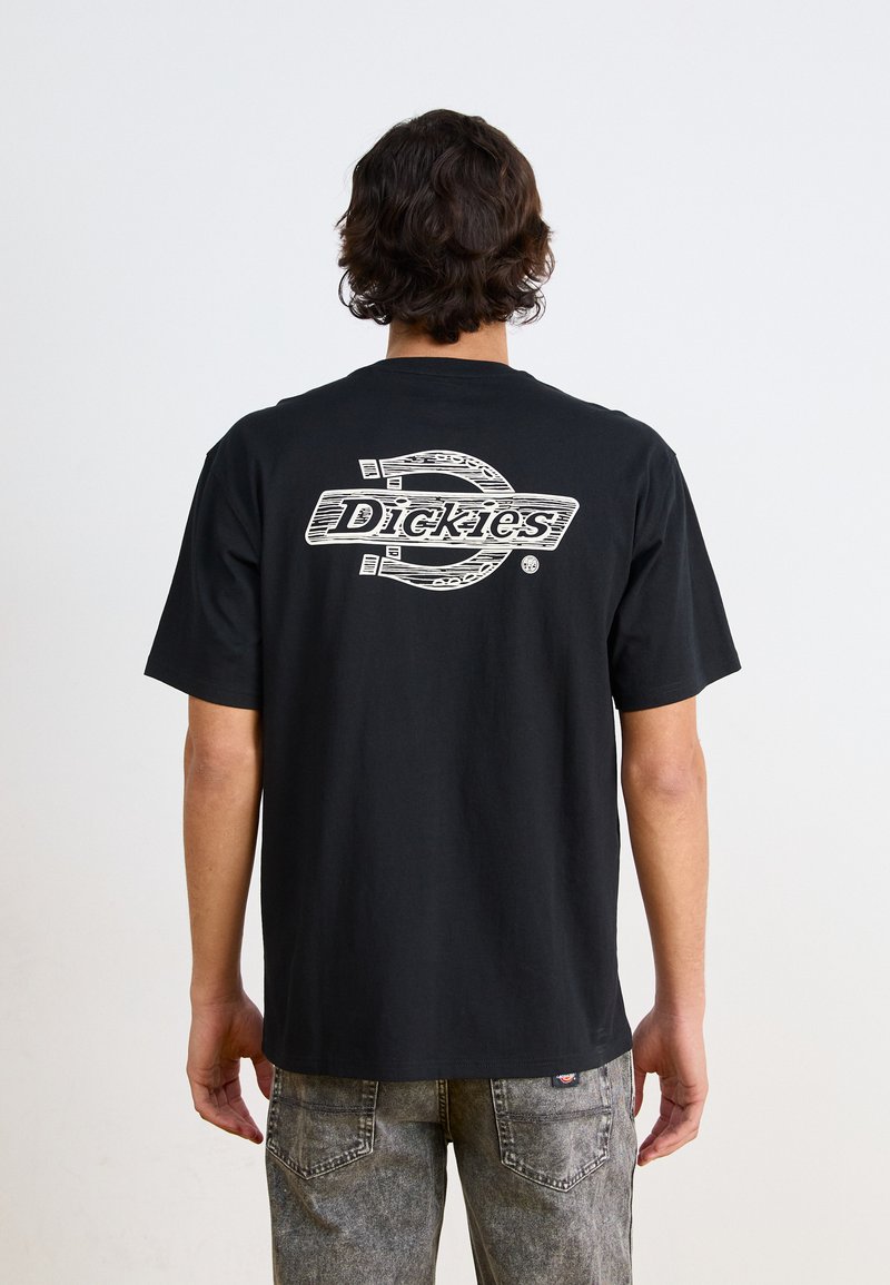 Juodas medvilninis marškinėlis su dideliu baltu "Dickies" logotipu ant nugaros, su trumpomis rankovėmis ir laisvu siluetu.