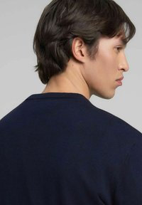 Maglione a maglia blu navy con scollo rotondo, mostrato da dietro, che mette in risalto la texture liscia e il design semplice.