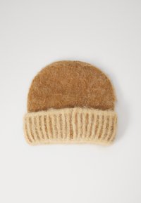 Bruine wollen beanie met een geribbelde beige manchet. De textuur is zacht en fuzzy, met een ronde bovenkant en een contrasterend breipatroon aan de basis.
