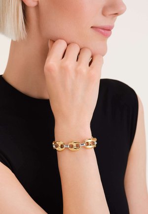 Gold- und Silberarmband mit ineinander greifenden Gliedern und einer polierten Oberfläche. Am Handgelenk getragen, hebt der hautfarbene Hintergrund die Sichtbarkeit hervor.