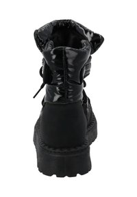 Botas de tobillo negras con un acabado brillante de charol, cuello acolchado y suela gruesa y estriada. Se ven los cordones y un detalle elástico.