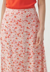 Jupe florale rose clair avec des fleurs rouges et violettes, design élégant avec une texture lisse et une ceinture, coupe légèrement fluide.