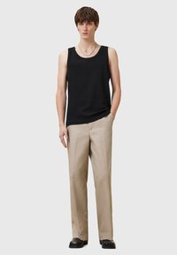 Svart ärmlös linne i mjukt tyg, tillsammans med beige raka byxor. Outfitten har en minimalistisk design och neutrala färger.