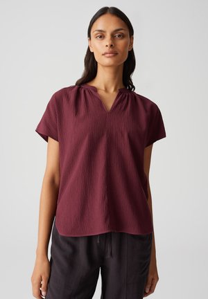 Blusa bordeaux a maniche corte con scollatura a V e motivo testurizzato. Tessuto leggero con una vestibilità rilassata e delicati plissettamenti sul colletto.