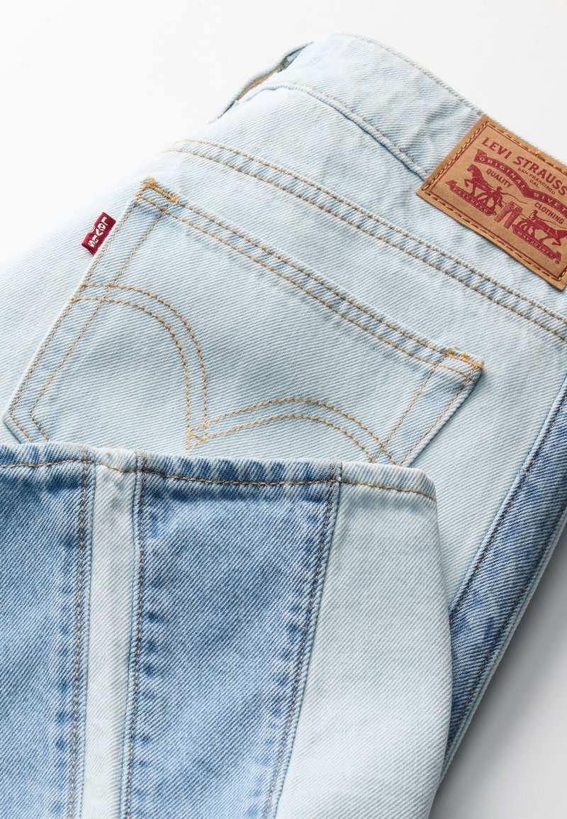 Hellblaue Jeans aus Denim mit einem Lederpatch, gelben Nähten und auffälligen Gesäßtaschen mit geschwungenen Nähten sowie einem klassischen Schnitt.