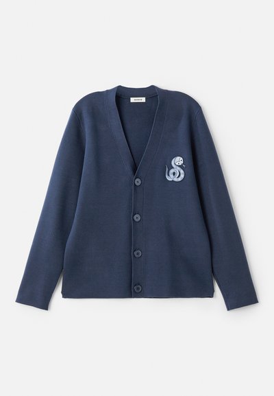 Jūras kara flotes kardigāns ar V veida kakla izgriezumu, garām piedurknēm un pogu aizdari. Kreklu rotā izšūts čūskas dizains uz kreisā krūts. Gluda tekstūra.