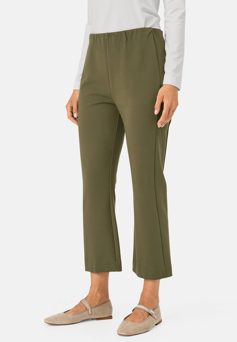 Olijfgroene stretchbroek met een elastische tailleband, cropped lengte en een gladde textuur, gecombineerd met beige flats met een banddetail.