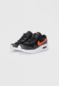 Fekete Nike sportcipők narancssárga részletekkel, hálós és bőrből készült felsőrésszel, fehér talppal és állítható pánttal a biztonságos illeszkedés érdekében.
