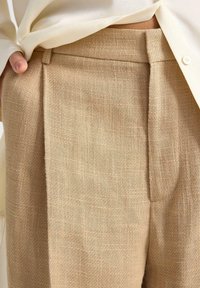 beige linnebyxor med en texturerad yta, som har veck framtill, snedställda fickor och en skräddarsydd midja för en strukturerad look.