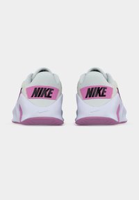 Παπούτσια Nike με γκρι ανοιχτό πλέγμα στο επάνω μέρος, ροζ λεπτομέρειες στη φτέρνα και λευκή εξωτερική σόλα από καουτσούκ με ρόζ σχέδιο πέλματος.