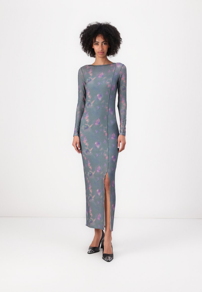 Long-sleeve, form-fitting dress in teal with pink floral pattern, side split, crew neckline, and smooth, stretch fabric. Black heels.