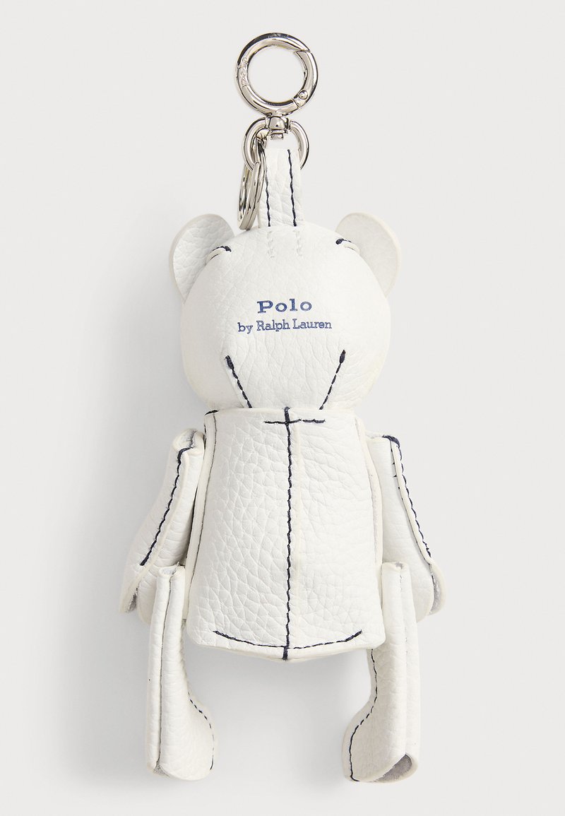 Witte teddybeervormige sleutelhanger van getextureerd leer met zwarte stiksels en "Polo by Ralph Lauren" geborduurd op de achterkant, bevestigd aan een zilveren ring.