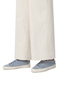 Sneakers blu in suede con lati perforati e suola in gomma bianca. I lacci abbinano il colore della scarpa. Indossati con pantaloni larghi di colore chiaro.
