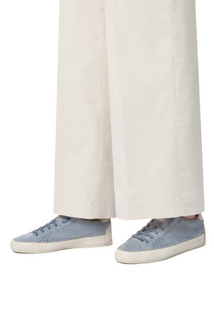 Blue suede sneakers with perforated sides and a white rubber sole. Laces match the shoe color. Worn with wide, light-colored trousers.